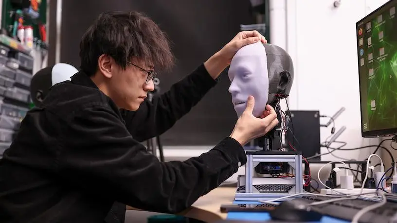 Lead researcher Yuhang Hu with Emo, wearing a silicone face