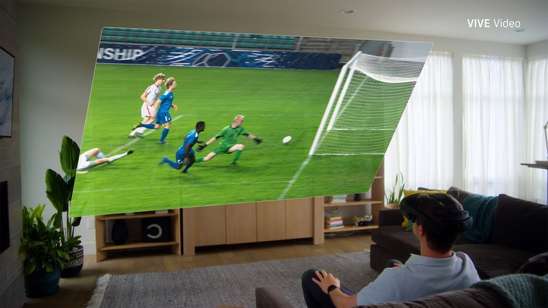 A man in a VIVE Focus Vision XR headset sits on a sofa, enjoying a soccer match on a large virtual screen.