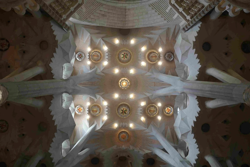 Ceiling view of a cathedral with geometric patterns, illuminated by soft lights and decorated with ornate designs.