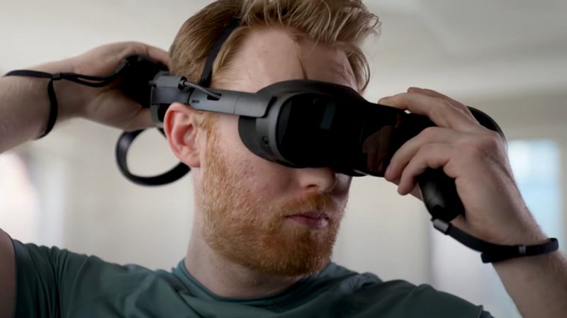 Man adjusting his VIVE XR Elite’s battery cradle with VIVE Controllers for XR Series in his hands regular..jpg