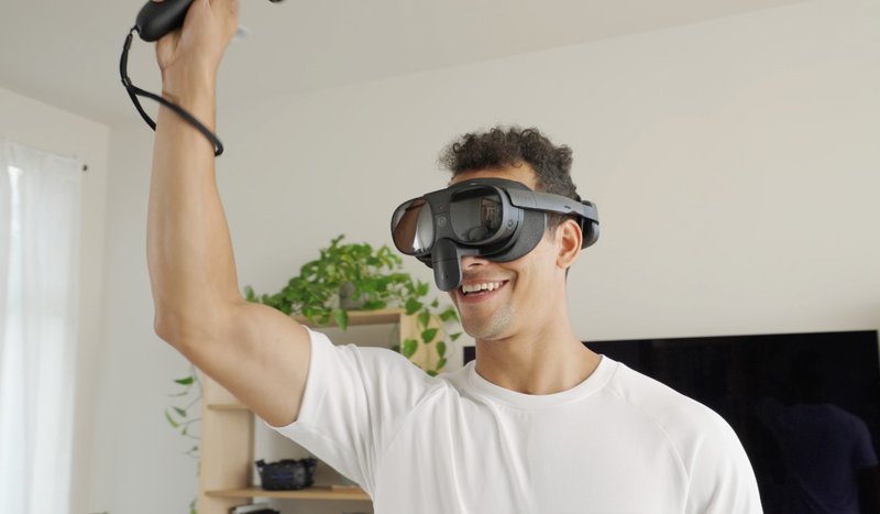 Man enjoying his time with the VIVE XR Elite and VIVE Full Face Tracker on, raising his right arm.