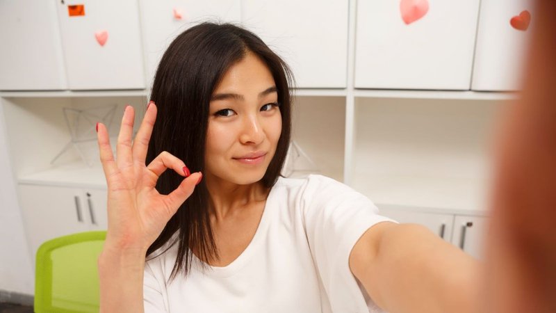 Selfie of a long-haired woman making an OK gesture with her fingers